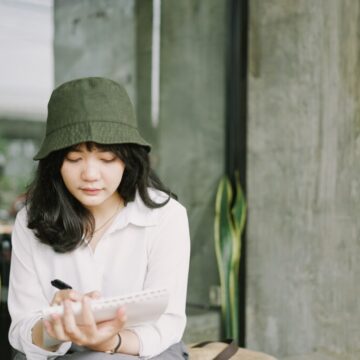 Lady wearing hat writing notes