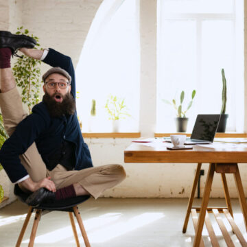 Emotive man stretching his leg at office while working on laptop. Businessman resting